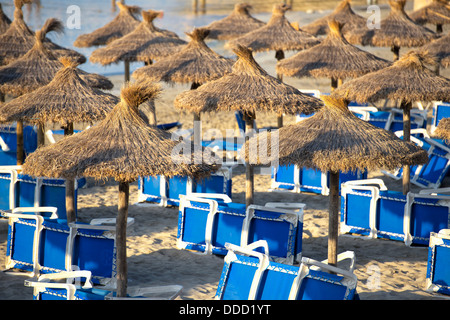 Beautiful Sandy Beach with Straw Umbrellas at Sunrise in Paguera, Majorca ( Balearic Islands - Spain ) Stock Photo