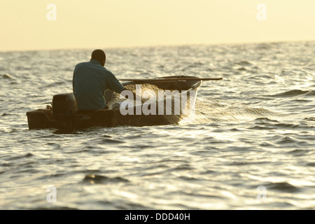A fisherman casts his nets from a small motorboat. Stock Photo