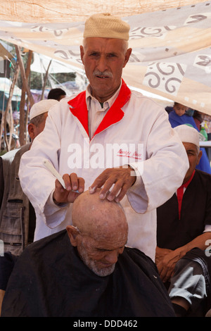 A old man has his hair cut in the barbers wish also sells 