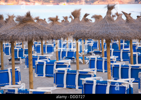 Beautiful Sandy Beach with Straw Umbrellas at Sunrise in Paguera, Majorca ( Balearic Islands - Spain ) Stock Photo