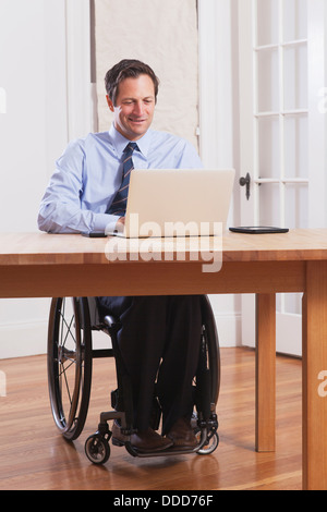 Businessman with spinal cord injury in a wheelchair working on laptop Stock Photo