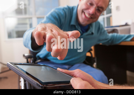 Two disabled men sitting in wheelchairs and using a digital tablet Stock Photo