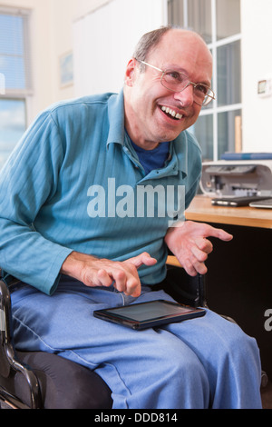 Man with Friedreich's Ataxia in wheelchair using a tablet with deformed hands Stock Photo