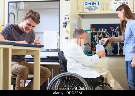 Professor spinal cord injury in wheelchair working students in an engineering lab filling container distilled water Stock Photo