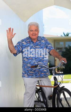 Senior man with polio waving his hand on bicycle with cane attached Stock Photo