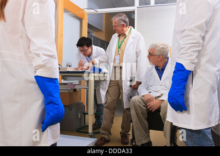 Professors talking engineering students wearing liquid nitrogen protective gloves reviewing laboratory log book chemistry Stock Photo