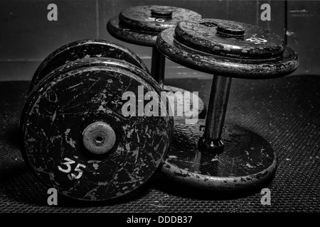 An old but well used set of dumbbells at the gym in black and white. Stock Photo