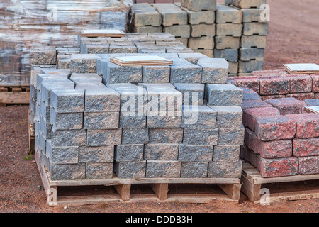 Stacks of various colored concrete pavers (paving stone) or patio blocks organized on wooden pallets and for sale in a retail se Stock Photo