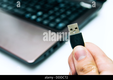 Man holding USB plug. Laptop in background Stock Photo
