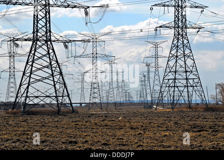 Field of many electrical transmission towers against cloudy sky. Stock Photo