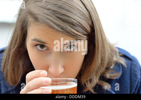 Young woman in coat drinking a beer looking at the camera Stock Photo