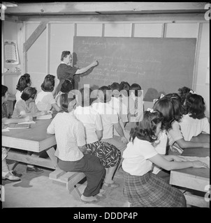 This image shows a group of students and their instructor at the Gila River Relocation Center in Arizona, where Japanese Americans were interned during World War II. The photo reflects the educational efforts within the internment camps. Stock Photo