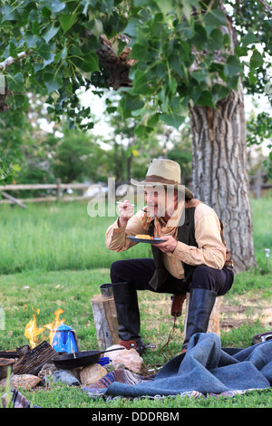 A cowboy preparing and eating breakfast at his campfire Stock Photo