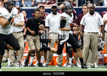 Aug. 31, 2013 - Houston, Texas, United States of America - August 31, 2103: Oklahoma State Cowboys quarterback J.W. Walsh (4) scrambles during the Advocare Texas Kickoff NCAA football game between the Mississippi State Bulldogs and the Oklahoma State Cowboys at Reliant Stadium in Houston, TX. Stock Photo