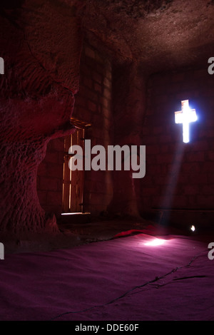 Light from a cross-shaped window shines on the red carpet of a rock cut church in Lalibela, Ethiopia Stock Photo