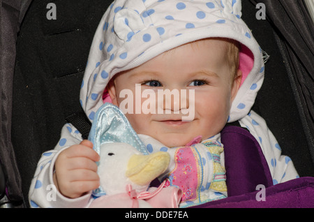 Smiling eight month old baby girl with Jemima Puddle Duck doll Stock Photo
