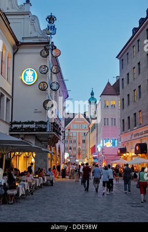 People walk in Platzl square illuminated at dusk. Munich, Bavaria, Germany. Stock Photo