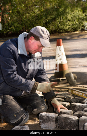 self building house, hard landscaping, workman laying reclaimed granite setts at entrance to driveway Stock Photo