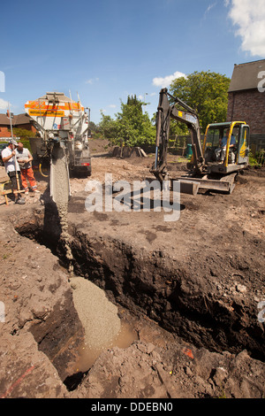 self building house, concrete foundations being poured after volvo digger has prepared the site Stock Photo