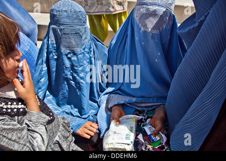 Afghan women wearing traditional full body covering called Burqa gather outside a community clinic after receiving medical supplies during an education seminar August 19, 2013 in the Deh Yak district, Ghazni province, Afghanistan. Stock Photo