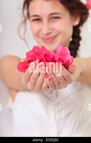 Smiling young woman holding flower petals in her hands Stock Photo
