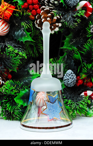 Glass Christmas hand bell with Christmas wreath to the rear. Stock Photo