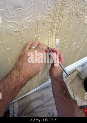 Traditional decorating, decorator, marking lincrusta traditional wallcovering to fit behind power socket Stock Photo