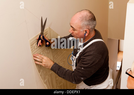 Traditional decorating, decorator trimming panel of lincrusta traditional wallcovering with scissors Stock Photo