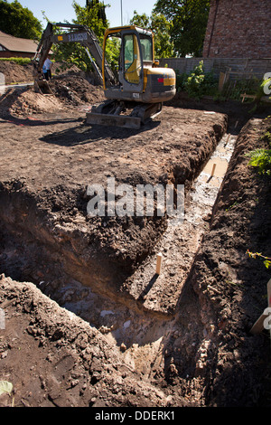 self building house, volvo digger preparing site after concrete foundations, have been poured Stock Photo