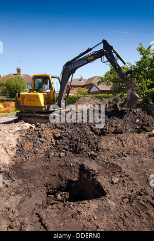 self building house, volvo digger preparing site by stripping back vegetation and topsoil from garden Stock Photo