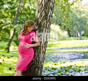 The young pregnant woman on walk in park Stock Photo