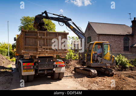 self building house, volvo digger preparing garden, loading spoil onto lorry to be dumped Stock Photo