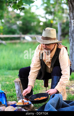 A cowboy preparing and eating breakfast at his campfire Stock Photo