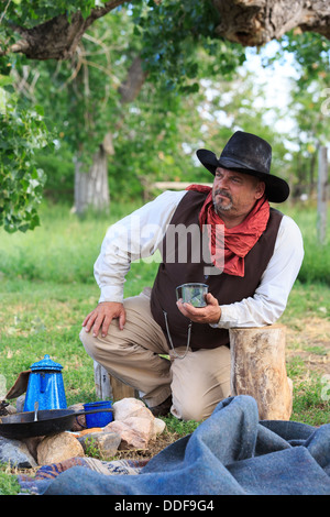 A cowboy preparing and eating breakfast at his campfire Stock Photo