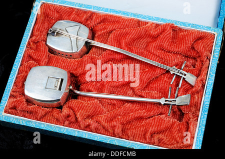 Two silver guitar shaped incense holders in a blue and red case. Stock Photo