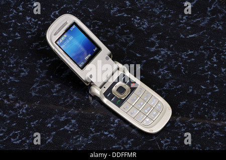 Clam shell/folding mobile phone against a dark background. Stock Photo