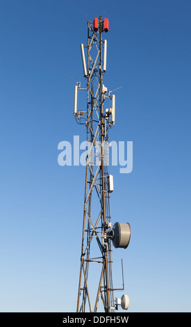 Communication radio tower with devices on blue sky background Stock Photo