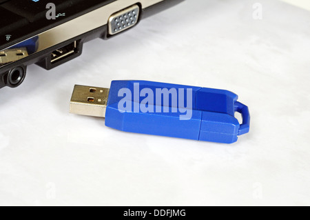 Blue USB stick sitting alongside a netbook against a white background. Stock Photo
