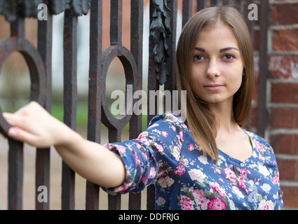 Portrait of a beautiful girl near the old rusty wrought fence. Stock Photo