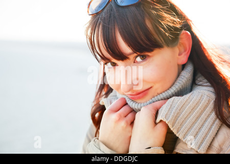 Portrait of a beautiful young woman standing by the sea on a sunny day in winter
