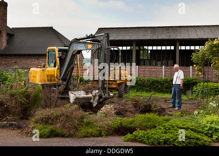 self building house, preparing site by stripping back vegetation and topsoil from garden with JCB digger Stock Photo