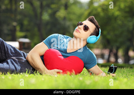 Handsome male lying on a grass with red heart listening music Stock Photo