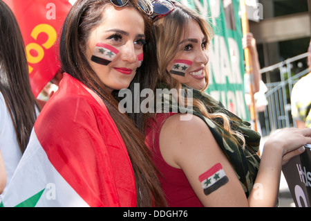 Demo against intervention in Syria. Young Syrian women with flags painted on their cheeks and one wrapped in a flag. Stock Photo