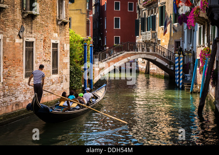 Gondola with tourists sailing on a water street in Venice Italy Stock Photo