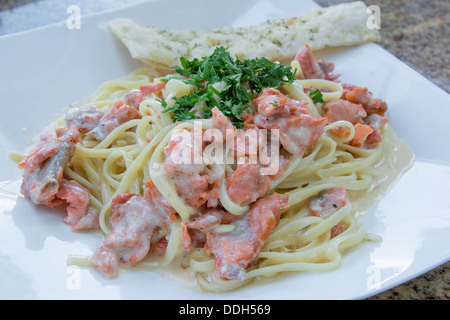 Linguine Pasta and Smoked Salmon Fish Cooked with Alfredo Sauce Garnished with Parsley Closeup Stock Photo