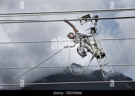 High-voltage service technician pulling a rope to get to the next pylon Stock Photo