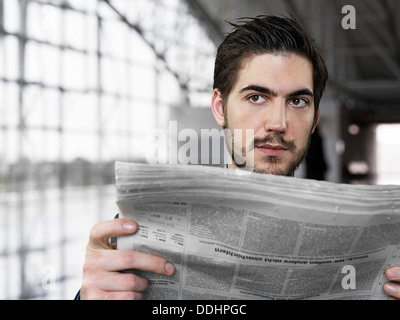 Businessman holding newspaper at airport, looking away Stock Photo