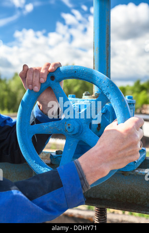 Hands close-up of mature manual worker turning stop-gate valve Stock Photo