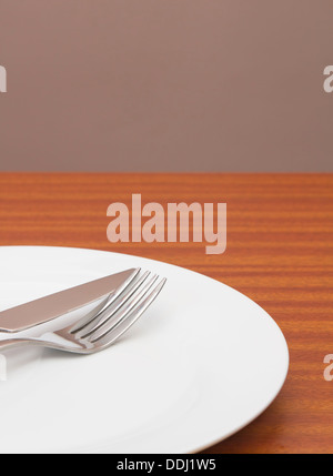 White place setting on table with wall behind Stock Photo