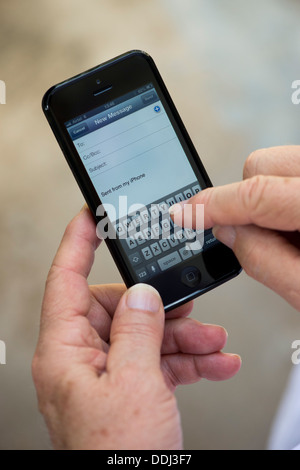 Senior man using Apple iphone 5 to write email Stock Photo